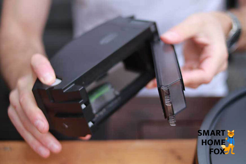 Der Staubbehälter des iRobot Roomba j7 wird mit Hilfe eines Knopfdruckes geöffnet.